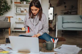 
		Young woman sitting in front of a laptop and writing
	